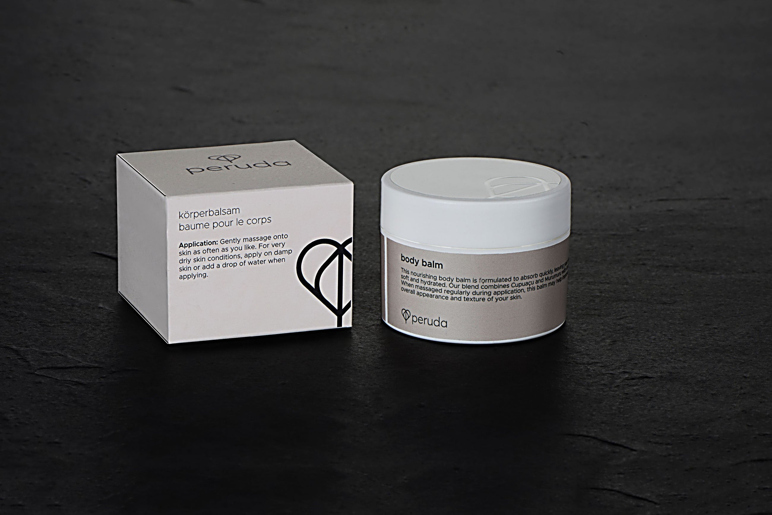 A white jar of Peruda body balm next to a beige box.
