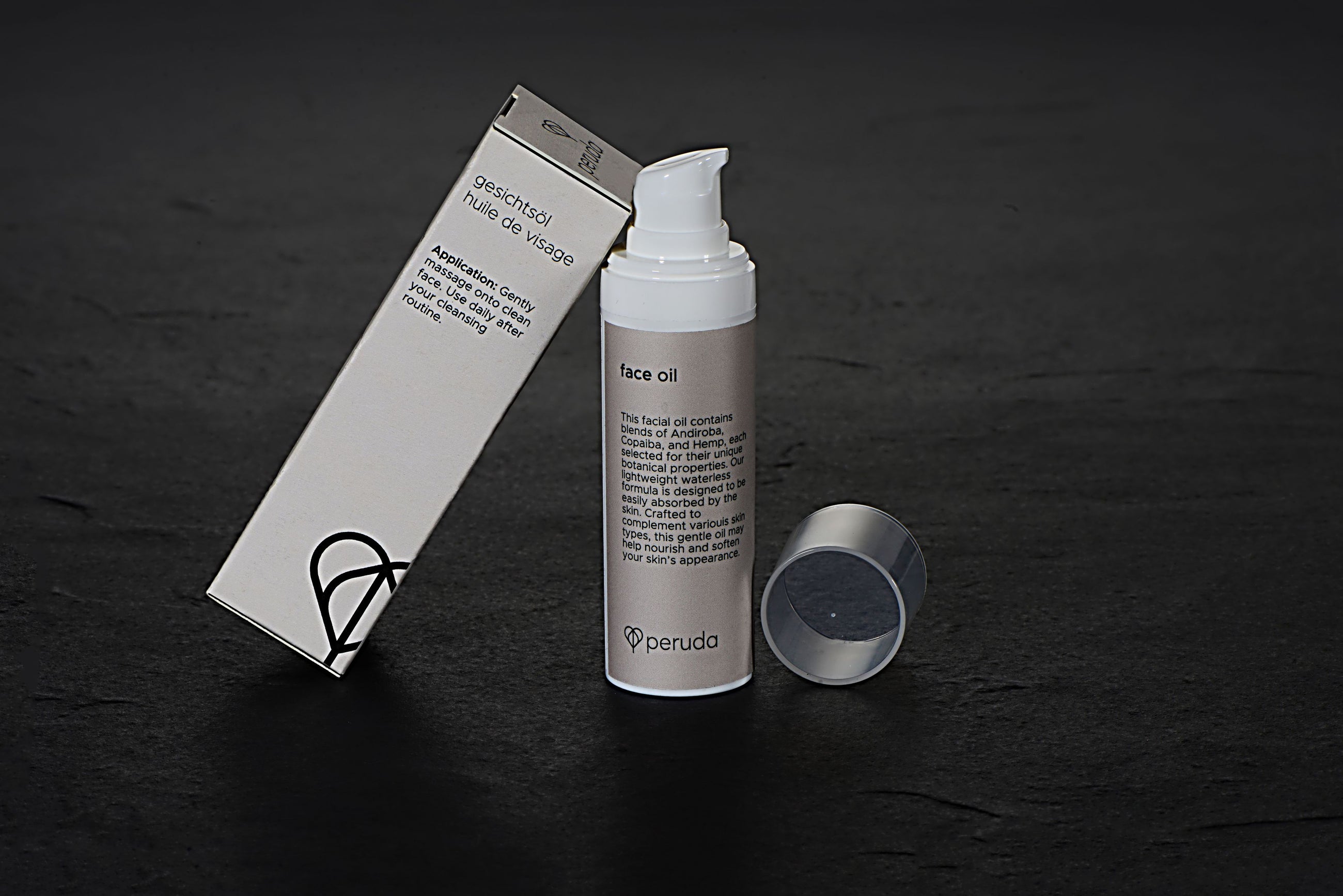 Peruda face oil in a white pump bottle next to a beige box.