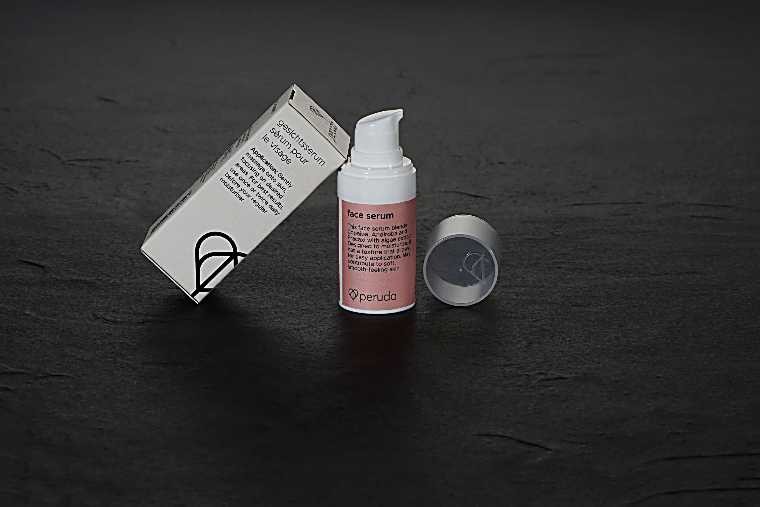 Peruda face serum in a white pump bottle with a pink label and beige box.