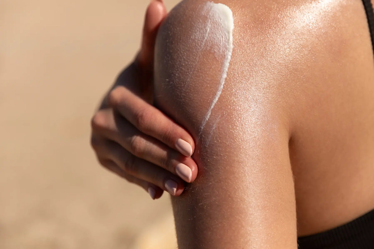 Female shoulder with hand applying sun cream