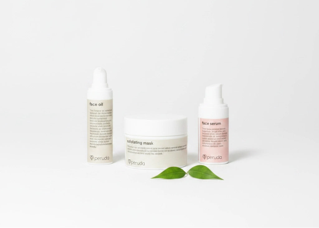 Three skincare products from the brand penuta arranged on a white background: a beige bottle labeled face oil, a white jar labeled infusing mask, and a pale pink bottle labeled face serum, with two green leaves in front.