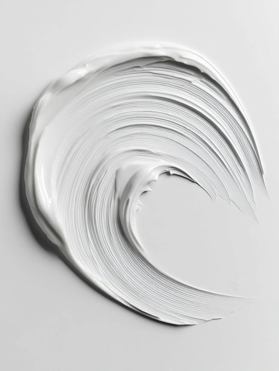 A thick, creamy white cosmetic cream swirled into a wave-like shape on a light gray background.