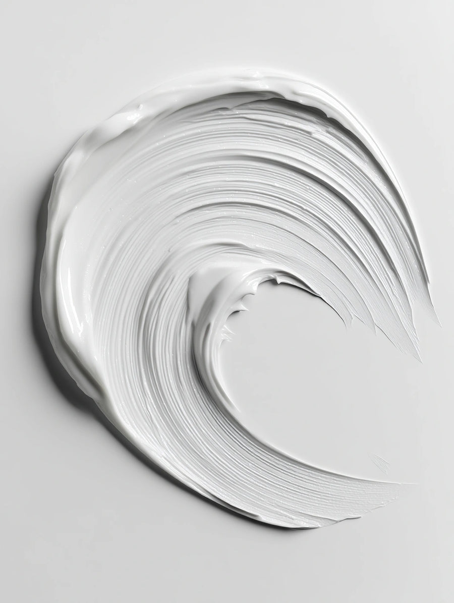 A thick, creamy white cosmetic cream swirled into a wave-like shape on a light gray background.