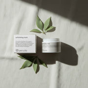 peruda skincare exfoliating mask jar and box with green leaves on a textured white fabric background