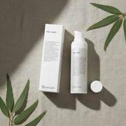 peruda skincare face wash with neem in a white pump bottle and box on a neutral linen background with green leaves